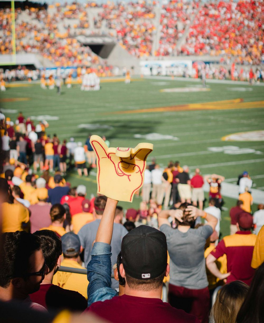 A fan raises a foam finger in a packed college football stadium